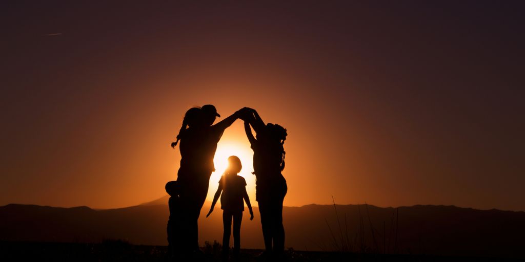 a group of people standing in front of a sunset